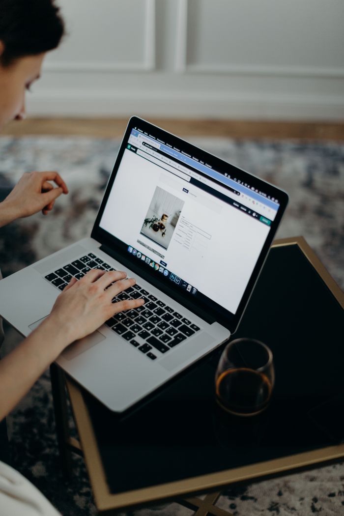 Close-up of a person working remotely on a laptop indoors. Ideal for remote work or technology themes.